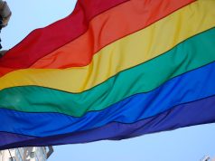 Sistema penal discrimina a personas LGBTI+ Bandera del orgullo LGBTI+ ondeando, símbolo de diversidad, igualdad y lucha por los derechos humanos.