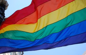 Sistema penal discrimina a personas LGBTI+ Bandera del orgullo LGBTI+ ondeando, símbolo de diversidad, igualdad y lucha por los derechos humanos.