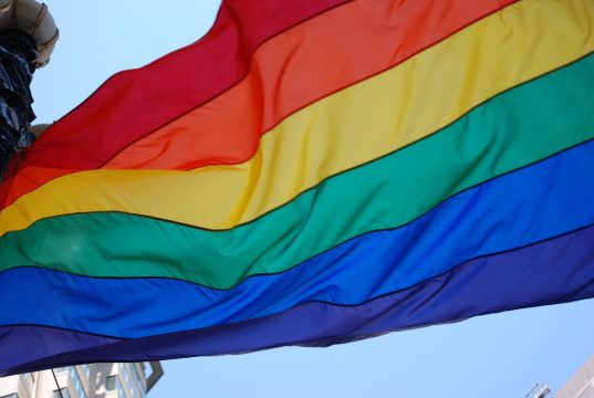 Sistema penal discrimina a personas LGBTI+ Bandera del orgullo LGBTI+ ondeando, símbolo de diversidad, igualdad y lucha por los derechos humanos.
